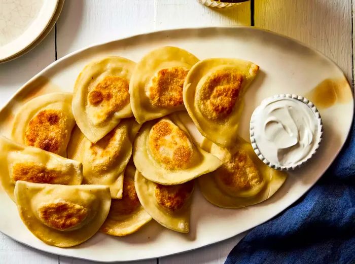 view of a plate of Polish pierogi, served with a side of sour cream