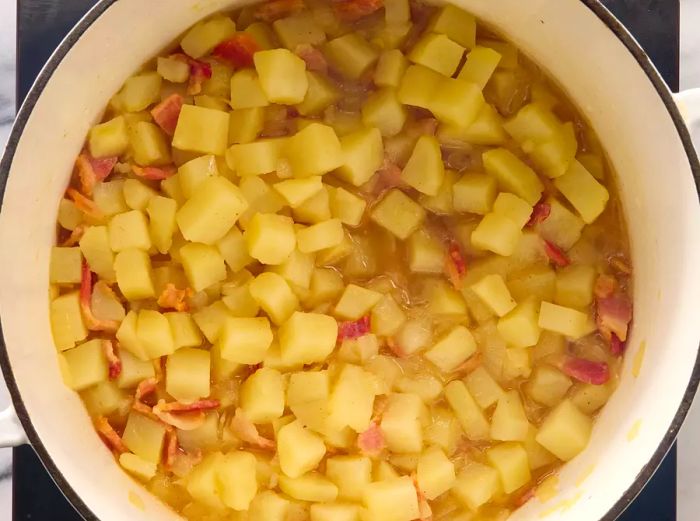 Potatoes and water cooking, simmering until the potatoes are tender