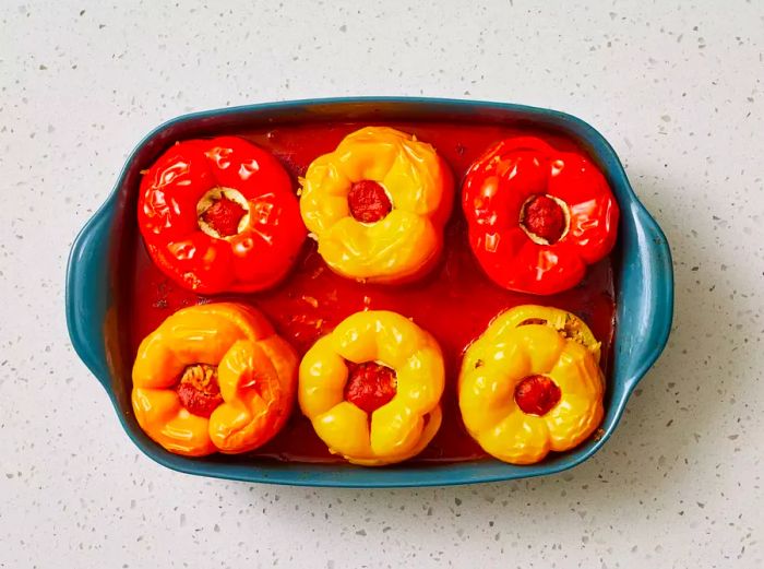 A baking dish featuring fully baked beef and rice stuffed bell peppers.