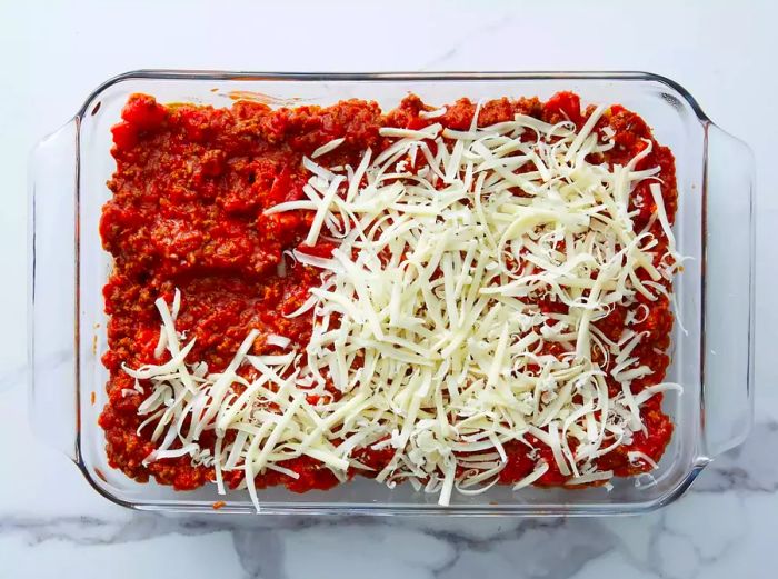 The sauce is evenly spread and topped with a layer of cheese.