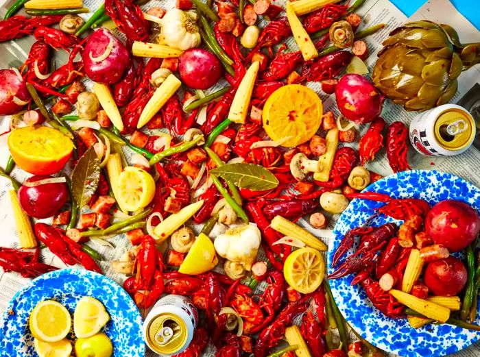 An overhead view of a Louisiana Crawfish Boil, served on newspapers with lemon slices and a cold beer.