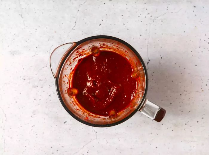 A blender jar filled with smooth chili sauce