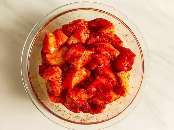 raw chicken marinated in a transparent bowl