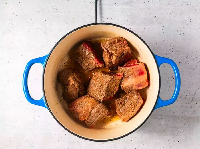 A pot with seared pieces of beef