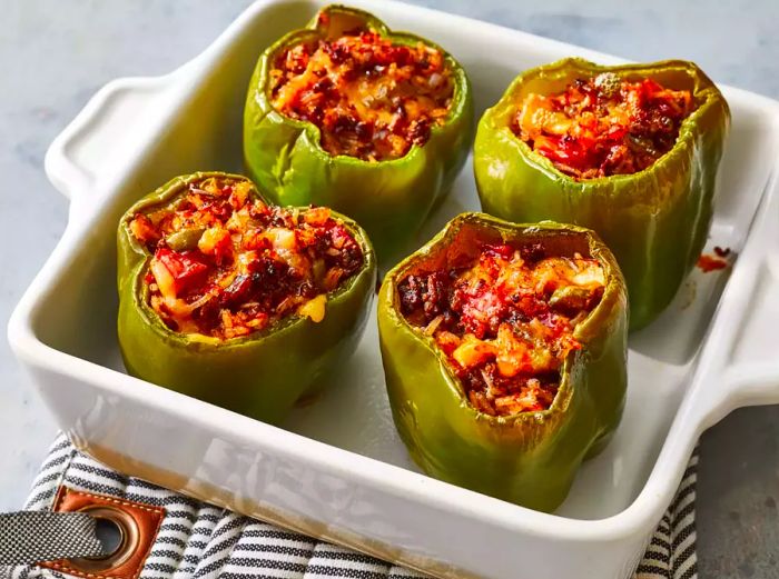 High-angle shot of a baking dish containing four stuffed, baked peppers