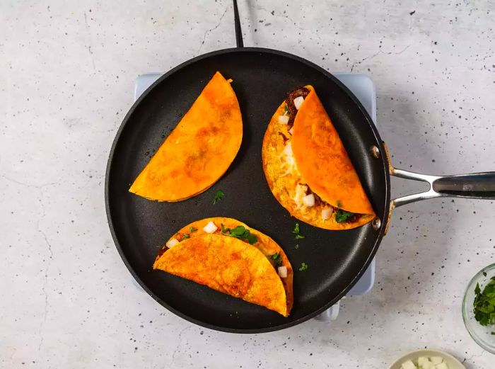 A small skillet filled with beef birria tacos