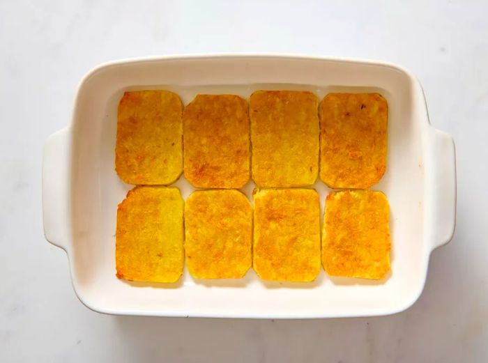 A baking dish lined with crispy hash brown patties