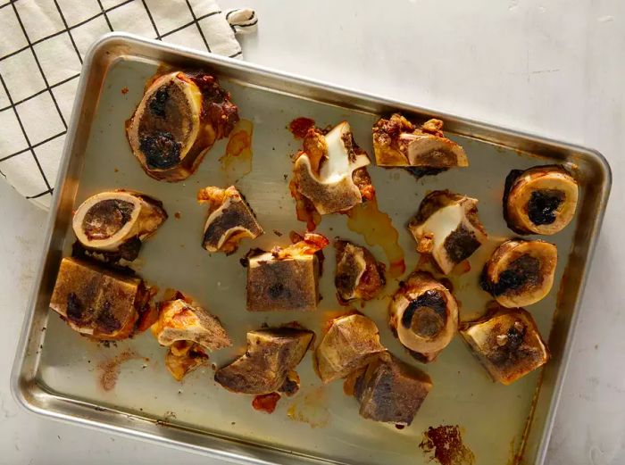 Beef bones on a baking sheet after roasting for about an hour.