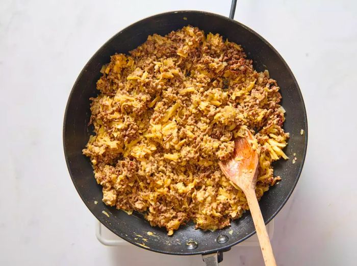 A skillet of cooked ground beef mixed with secret sauce and melted cheese