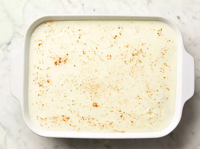 Top view of béchamel sauce spread over a baking dish.