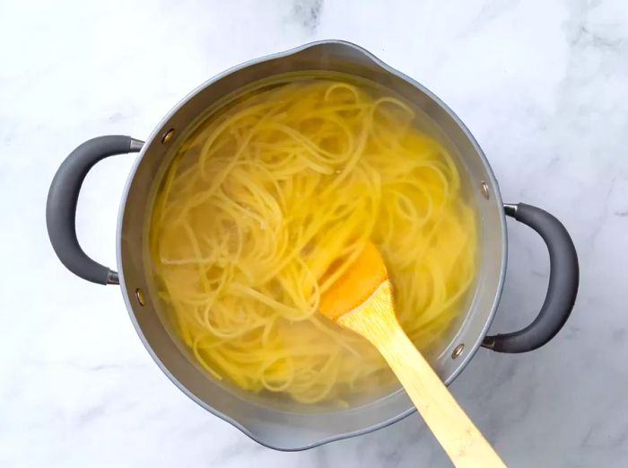 A large pot with linguine cooking in hot water