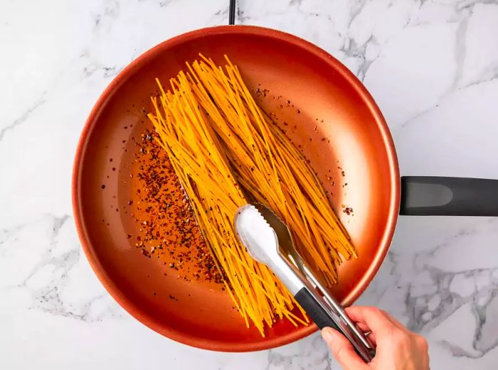 Spaghetti noodles toasting in the hot olive oil.