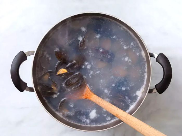 A pot of boiling water with mussels and littleneck clams inside