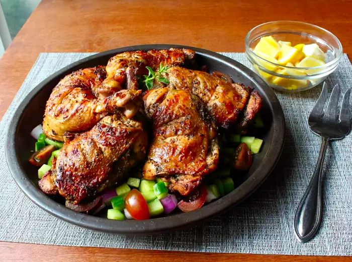 Platter of Chef John's Grilled Greek Chicken served over a bed of cucumbers, tomatoes, and red onions