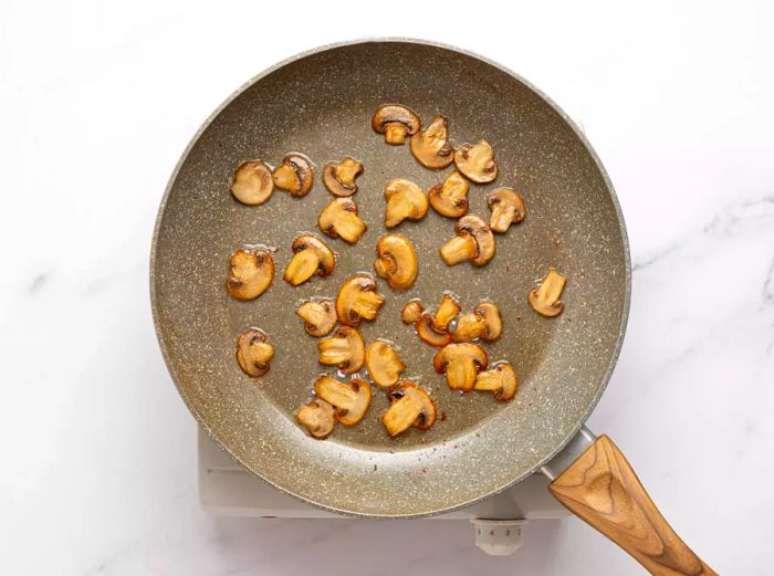 Mushrooms being sautéed in a skillet.