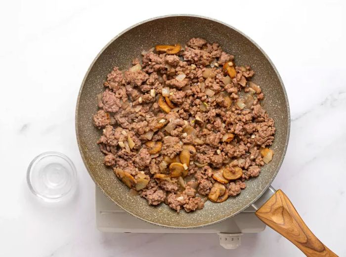 Ground beef and mushrooms sautéing in a skillet.