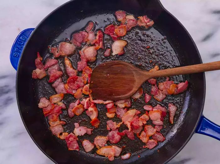 A cast iron skillet filled with chopped bacon.