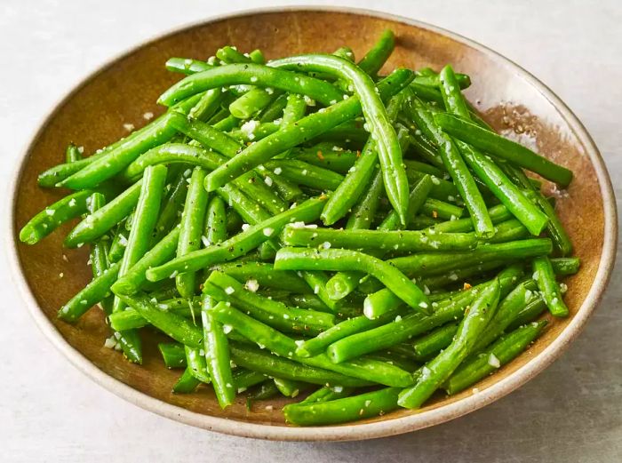 A close-up shot of a bowl filled with buttery garlic green beans