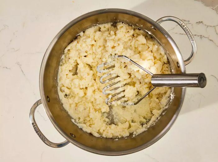 A large pot of potatoes and garlic mashed with creamy milk and butter