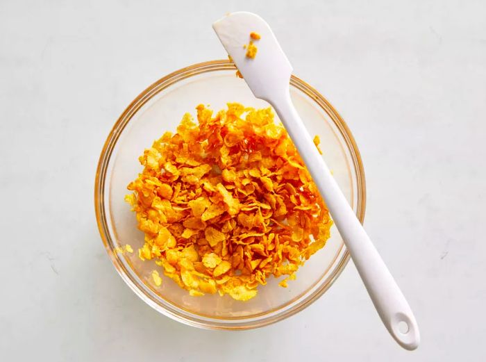 A small bowl containing cornflakes mixed with melted butter