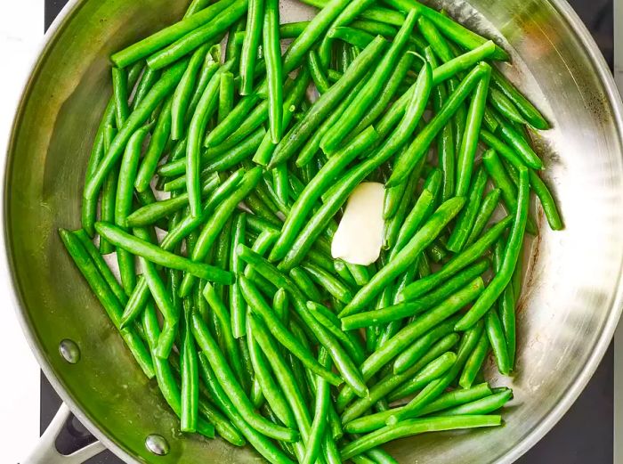 Aerial view of green beans with melted butter in a pan