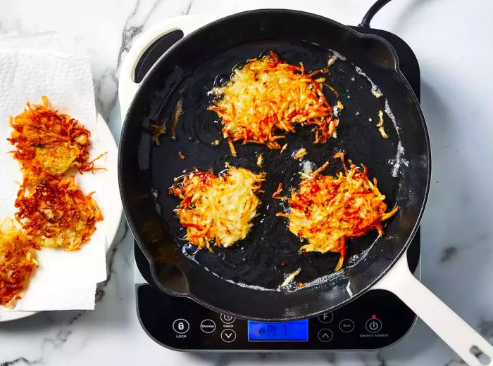 pancakes cooked and placed on a plate lined with paper towels to absorb excess oil