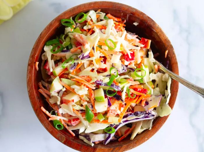 Vibrant apple coleslaw served in a wooden bowl