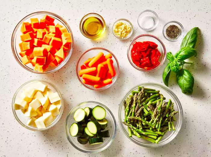 A top-down view of all the ingredients for the roasted vegetable medley, neatly arranged in bowls on the kitchen counter.