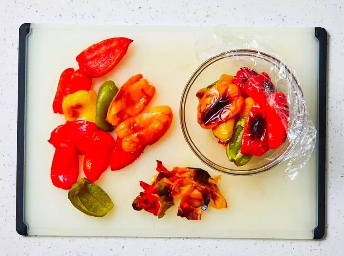 A cutting board with roasted bell peppers, their skins removed