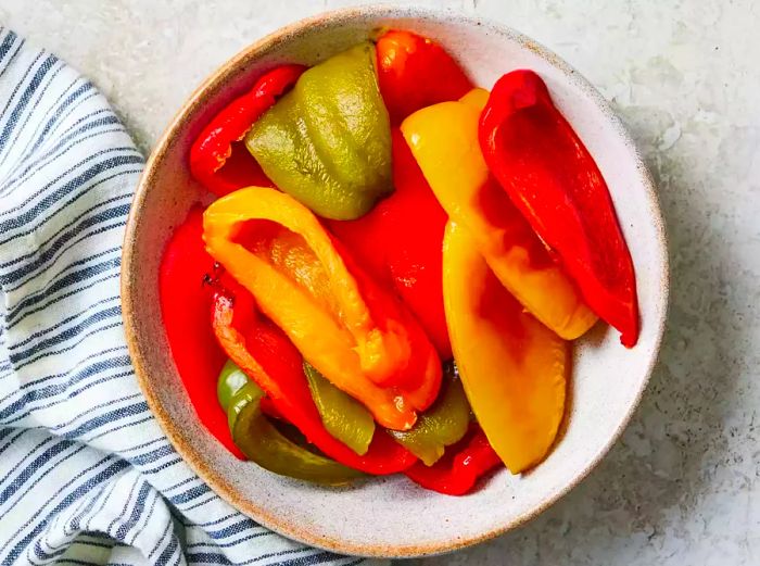 A bowl filled with roasted yellow, green, orange, and red peppers