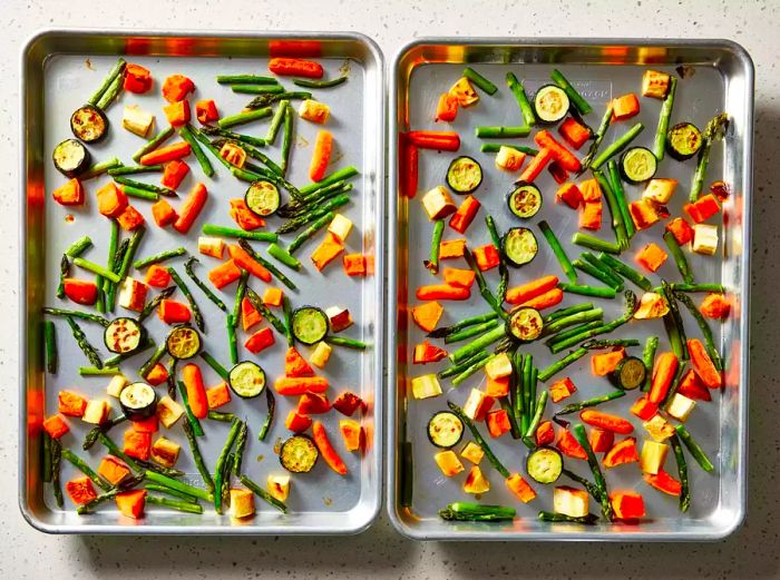 Two baking sheets filled with perfectly roasted mixed vegetables, left to cool down.