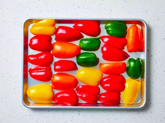 A baking sheet with bell pepper quarters, cut-side down