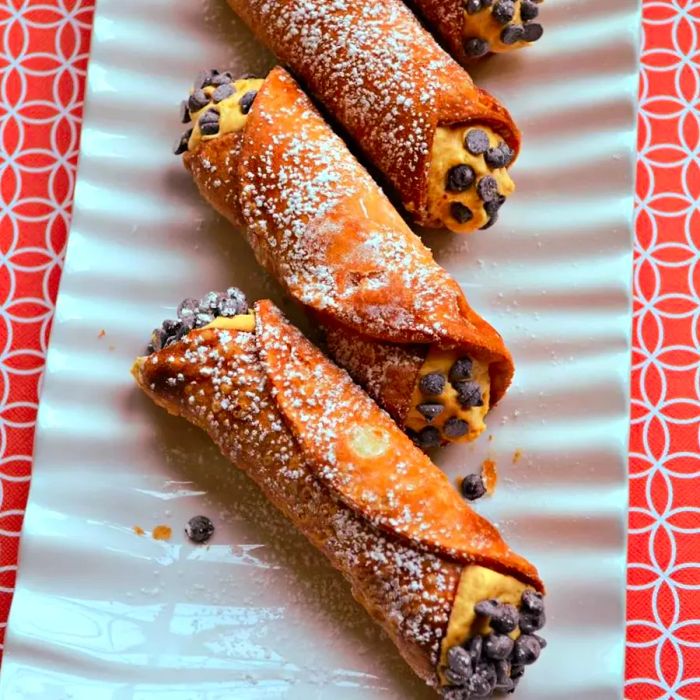 A platter of three cannolis, each filled with a creamy pumpkin filling.