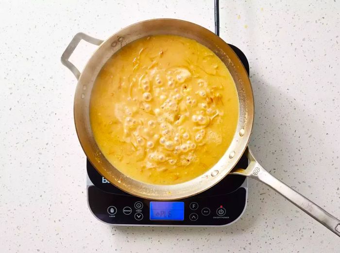 A pan of brown gravy gently simmering on the stove.