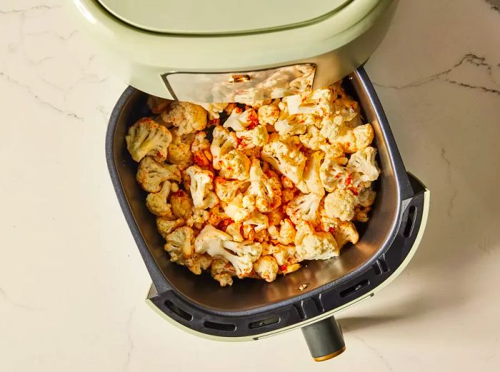 Cauliflower placed in the air fryer basket, ready to cook.
