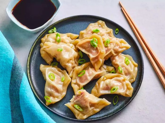 An overhead view of pork dumplings served on a plate, garnished with fresh green onions.