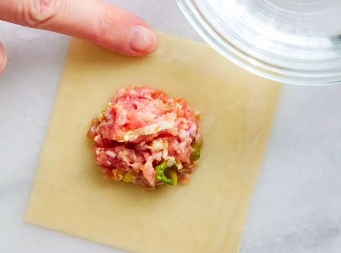 Filling placed onto the wonton wrapper, with edges sealed using water.