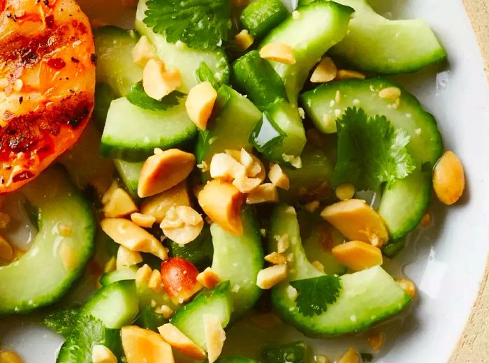 close-up of a Thai cucumber salad with peanuts and herbs on a plate