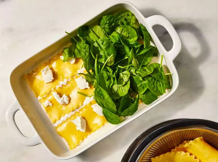 Baking dish with layers of lasagna noodles, ricotta, and spinach