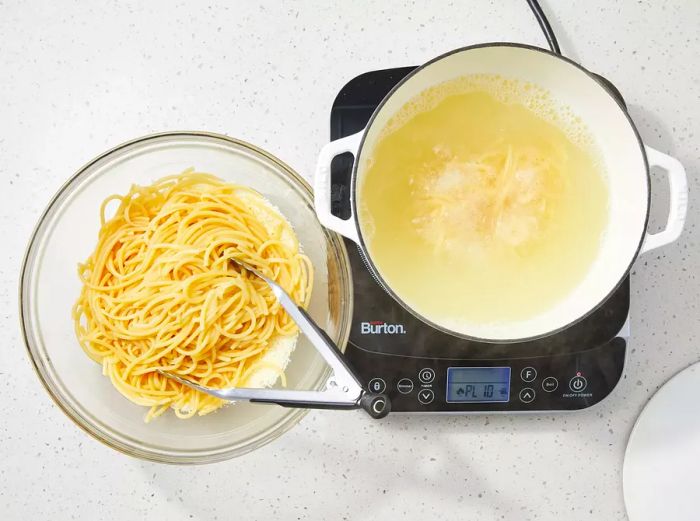 Noodles lifted with tongs and placed directly on top of the cheese.