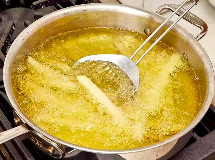 A high-angle view of fries frying in hot oil on the stovetop