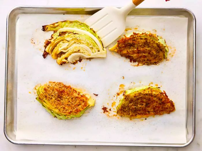 Cabbage wedges being flipped to allow the Parmesan crust to become golden-brown.