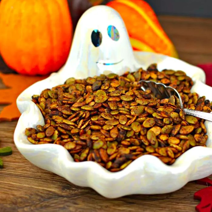 A bowl of seasoned pumpkin seeds shaped like a ghost