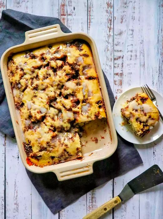 A sheet pan of coffee cake with a slice missing, and a piece of cake on a plate next to the pan.