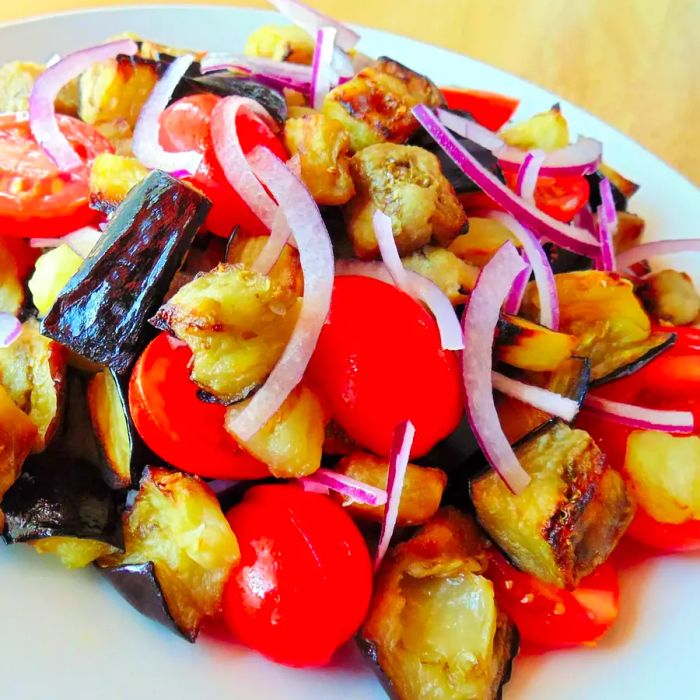 A fresh eggplant and tomato salad served on a white plate