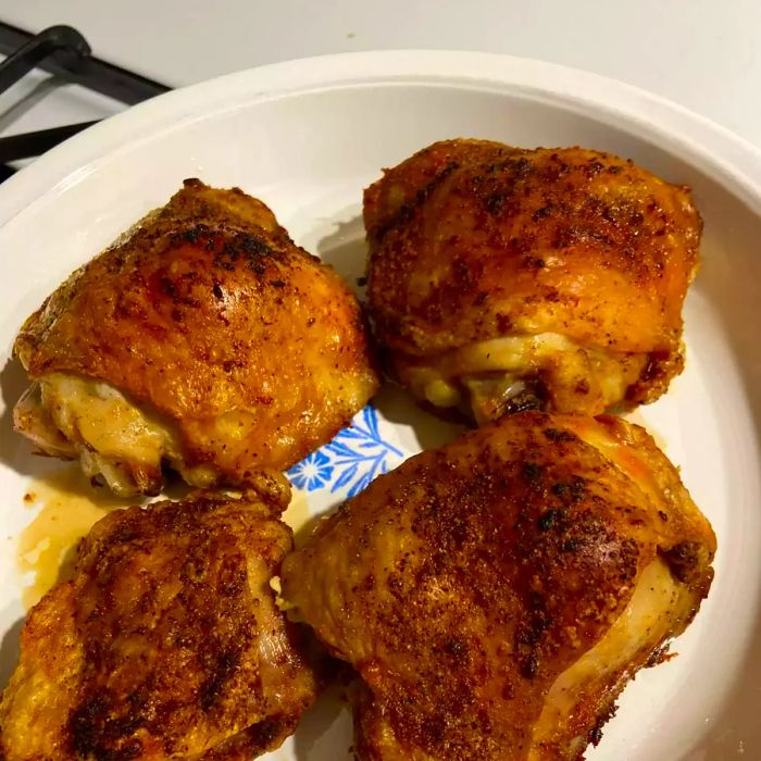 A plate of golden, crispy Air Fryer Chicken Thighs served on a white dish.