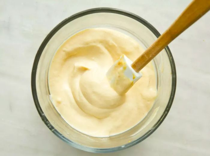 A top-down view of a mixture of mayonnaise and mustard in a glass bowl.
