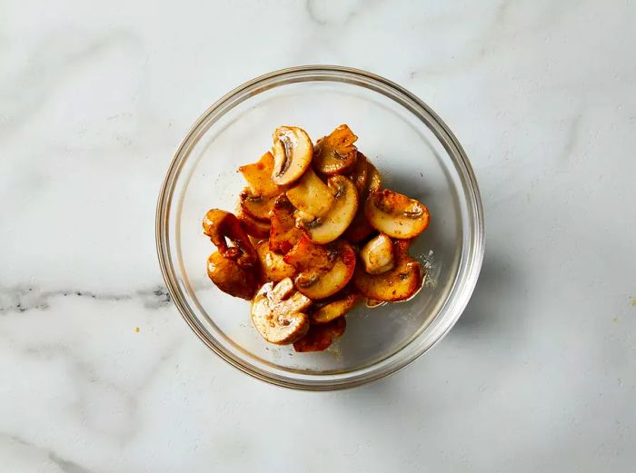 A top-down view of cooked mushrooms placed in a small glass bowl.