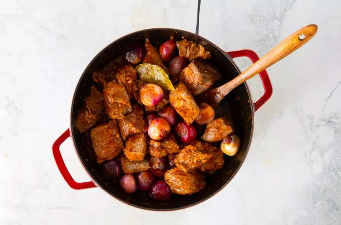 Chunks of beef and shallots simmering in the pot.