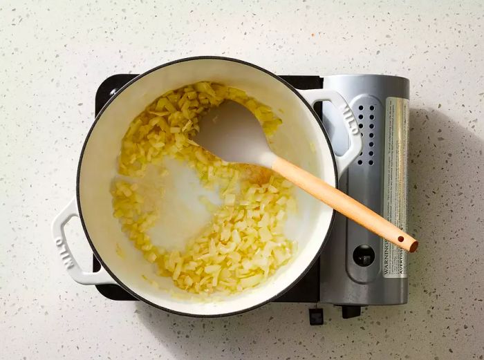 An overhead view of diced onion and butter cooking in a saucepan